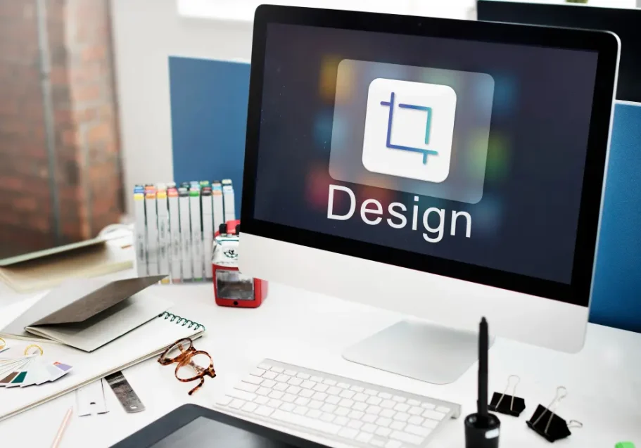 Gemeinsames Verfeinern Ein Computerbildschirm mit der Aufschrift "Design" und Büromaterialien im Hintergrund.