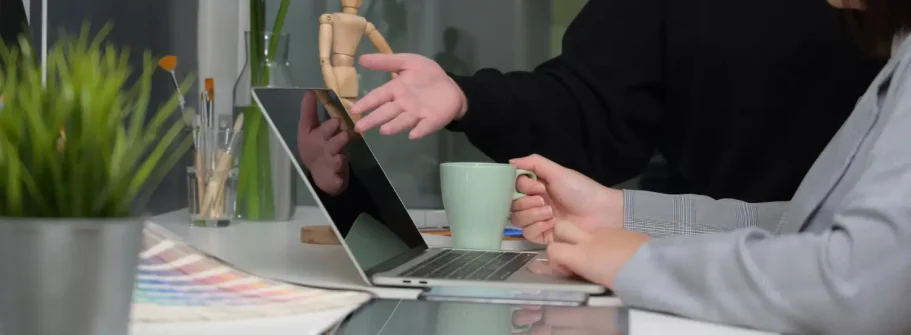 Souveräner Marktauftritt Zwei Personen diskutieren am Tisch, während sie auf einen Laptop zeigen.