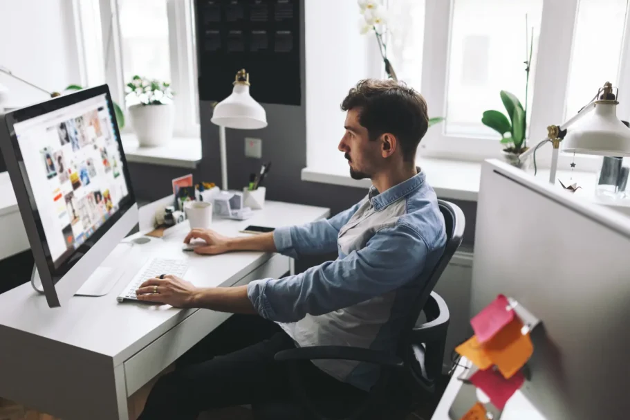 Strategische Analyse Mann sitzt am Schreibtisch und arbeitet an einem Computer mit verschiedenen Designs.